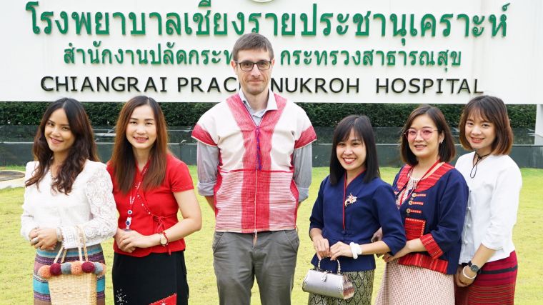 Chiangrai Clinical Research Unit Team, with from left to right: Nipaphan Kanthawang (Bee), Nidanuch Tasak (Pui), Carlo Perrone, Nongyao Khatta (Ann), Ploypatcha Kaewwiset (Maew), Areerat Thaiprakong (Zulin). They stand in front of a banner that says Chiangrai Prachanukroh Hospital (in Thai as well, first row) and Office of the permanent Secretary of Public Health (second row); Chiangrai Prachanukroh Hospital (third row)