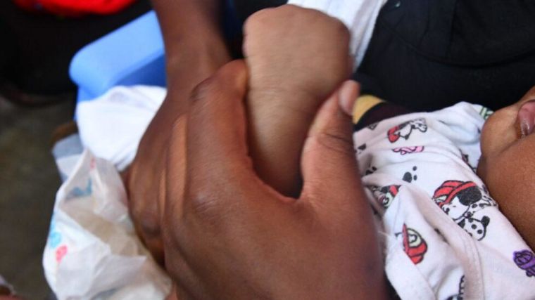 Close up on hands holding a baby's arm