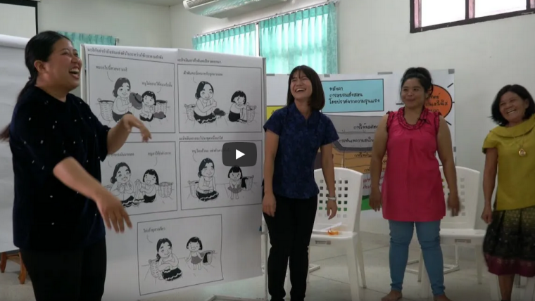 Thai participants to a workshop about the project Parenting for Life discuss in front of illustrations of parent-child typical behaviour
