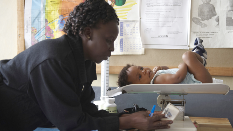 Healthcare worker weighing a baby