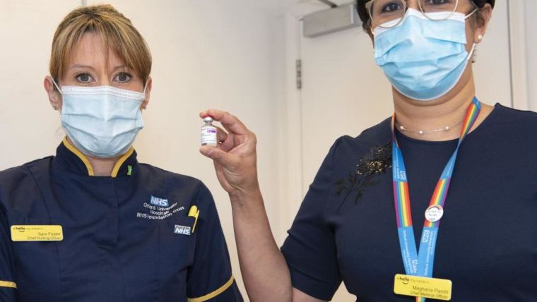 Two healthcare worker holding a vial of the Oxford-AstraZeneca vaccine