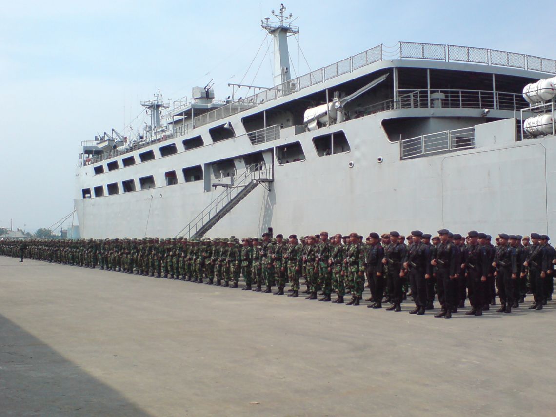 About 500 soldiers stand in military formation at a port on Java in front of their transport ship.